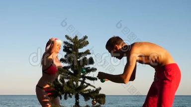 两个戴着圣诞帽的男人<strong>和女孩</strong>在海滩上迎接新年<strong>和</strong>圣诞节。 把<strong>圣诞树</strong>装饰在<strong>圣诞树</strong>上
